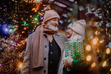 Happy senior couple enjoying outdoor christmas market, buying gifts. - HPIF11178