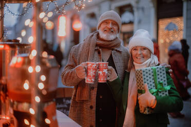 Glückliches älteres Paar genießt den Weihnachtsmarkt im Freien und kauft Geschenke. - HPIF11179