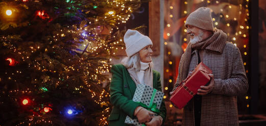 Glückliches älteres Paar genießt den Weihnachtsmarkt im Freien und kauft Geschenke. - HPIF11182
