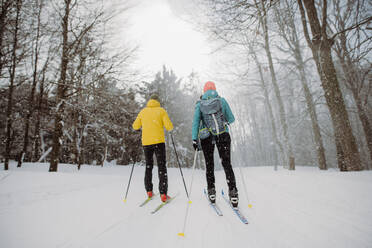 Älteres Paar beim gemeinsamen Skifahren inmitten eines verschneiten Waldes - HPIF11202