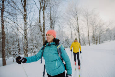 Senior couple skiing togetherin the middle of snowy forest - HPIF11203