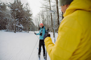 Älteres Paar beim gemeinsamen Skifahren inmitten eines verschneiten Waldes - HPIF11204
