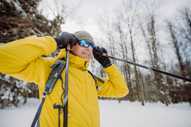 Senior man putting on snow glasses,preparing for ride in forest. - HPIF11205