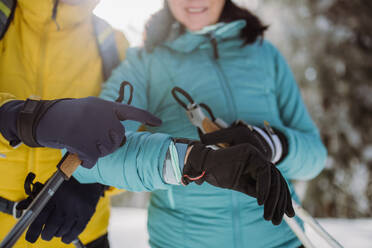 Nahaufnahme eines älteren Paares, das beim Skifahren auf eine Smartwatch schaut. - HPIF11206