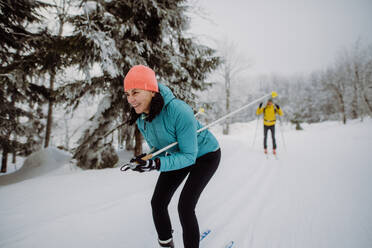 Senior couple skiing together in the middle of snowy forest - HPIF11250