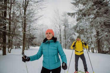 Älteres Paar beim Skifahren inmitten eines verschneiten Waldes. - HPIF11253