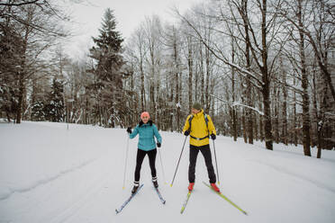 Älteres Paar beim gemeinsamen Skifahren inmitten eines verschneiten Waldes - HPIF11257