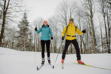 Älteres Paar beim gemeinsamen Skifahren inmitten eines verschneiten Waldes - HPIF11258