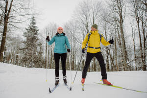 Älteres Paar beim gemeinsamen Skifahren inmitten eines verschneiten Waldes - HPIF11258