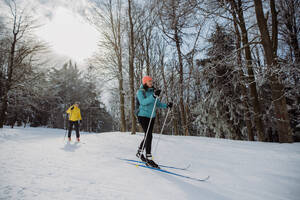 Älteres Paar beim gemeinsamen Skifahren inmitten eines verschneiten Waldes - HPIF11263