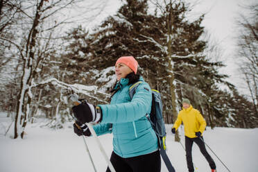 Älteres Paar beim gemeinsamen Skifahren inmitten eines verschneiten Waldes - HPIF11268