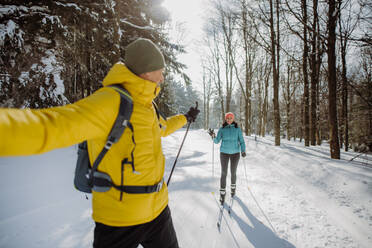 Älteres Paar beim Skifahren inmitten eines verschneiten Waldes. - HPIF11273