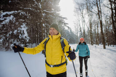 Älteres Paar beim gemeinsamen Skifahren inmitten eines verschneiten Waldes - HPIF11275