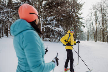 Älteres Paar beim gemeinsamen Skifahren inmitten eines verschneiten Waldes - HPIF11276