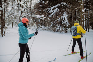 Älteres Paar beim gemeinsamen Skifahren inmitten eines verschneiten Waldes - HPIF11277