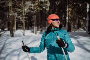 Ältere Frau beim Skifahren allein inmitten eines verschneiten Waldes. - HPIF11282