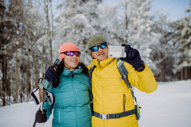 Senior couple taking selfie during cross country skiing in snowy nature. - HPIF11286