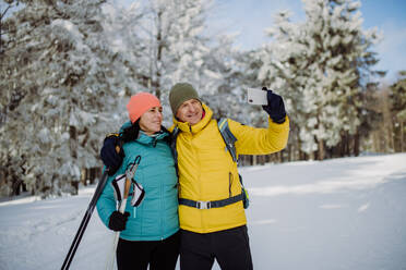 Senior couple taking selfie during cross country skiing in snowy nature. - HPIF11287