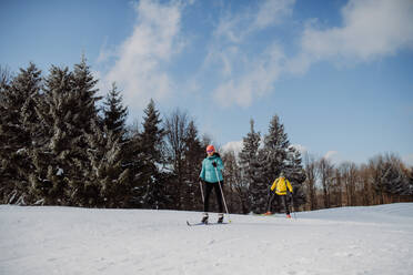 Älteres Paar beim Skifahren inmitten eines verschneiten Waldes. - HPIF11298