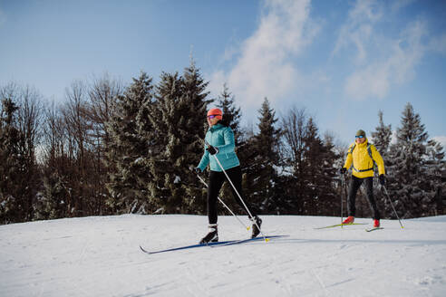 Älteres Paar beim Skifahren inmitten eines verschneiten Waldes. - HPIF11299