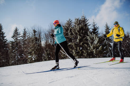 Älteres Paar beim gemeinsamen Skifahren inmitten eines verschneiten Waldes - HPIF11300