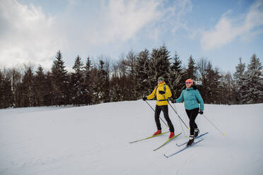 Älteres Paar beim Skifahren inmitten eines verschneiten Waldes. - HPIF11301