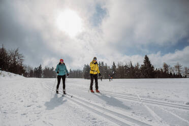 Älteres Paar beim Skifahren inmitten eines verschneiten Waldes. - HPIF11304