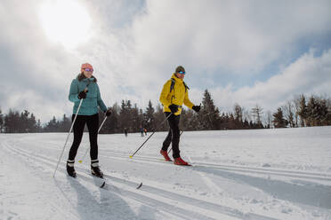 Älteres Paar beim gemeinsamen Skifahren inmitten eines verschneiten Waldes - HPIF11305