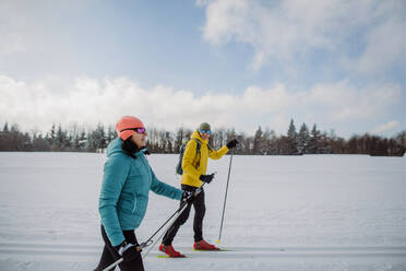 Älteres Paar beim gemeinsamen Skifahren inmitten eines verschneiten Waldes - HPIF11307