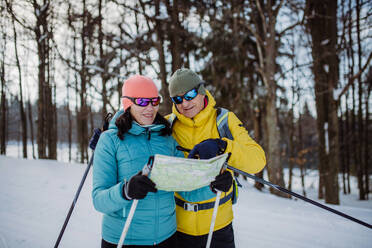 Senior couple looking at paper map during cross country skiing in snowy nature. - HPIF11311