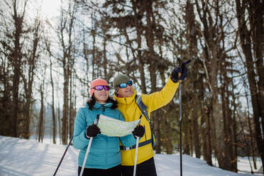 Senior couple looking at paper map during cross country skiing in snowy nature. - HPIF11312