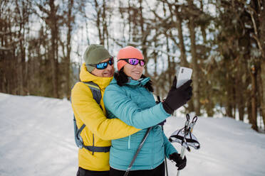 Senior couple taking selfie during cross country skiing in snowy nature. - HPIF11314