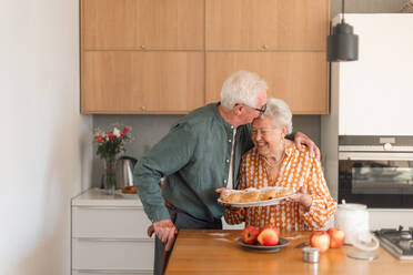 Glückliches älteres Ehepaar mit selbstgebackenem süßem Zopfbrot mit Rosinen. - HPIF11352