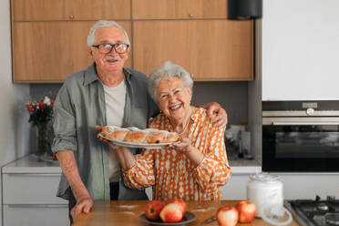 Glückliches älteres Ehepaar mit selbstgebackenem süßem Zopfbrot mit Rosinen. - HPIF11353