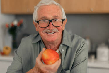 Porträt eines älteren Mannes mit Äpfeln in der Hand in einer Küche. - HPIF11355