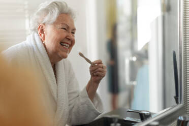 Ältere Frau putzt sich die Zähne mit einer Holzbürste im Badezimmer, nachhaltiger Lebensstil. - HPIF11433