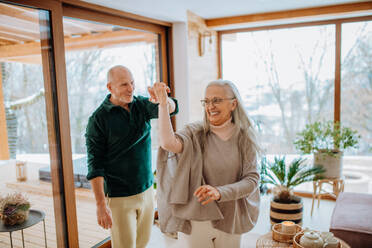 Senior couple in love dancing together in their nice modern living room. - HPIF11526