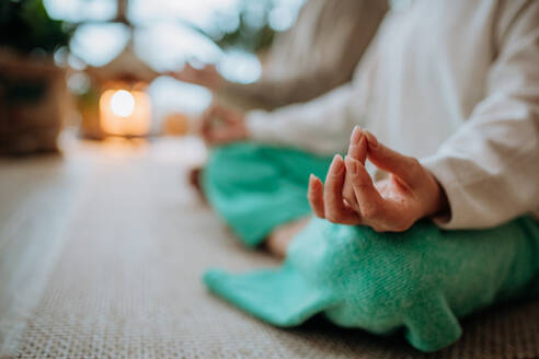 Close-up of senior couple meditating together in their living room during a cold autumn day. - HPIF11537