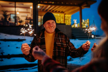 Happy senior couple celebrating new year with the sparklers, enjoying winter evening. - HPIF11561