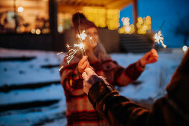 Happy senior couple celebrating new year with the sparklers, enjoying winter evening. - HPIF11562