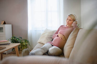 Pregnant woman sitting in a bed, listening music and enjoying time for herself. - HPIF11633