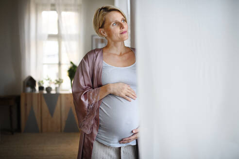 Glückliche schwangere Frau, die zu Hause ihren Bauch streichelt. - HPIF11636
