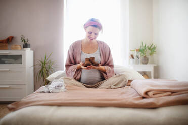 Glückliche schwangere Frau hält einen kleinen Schuh für ihr Baby. - HPIF11647