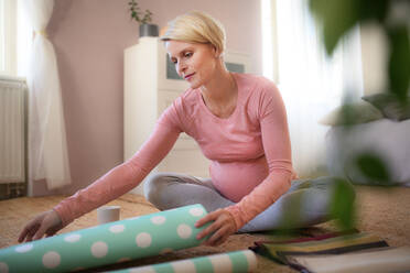 Glückliche schwangere Frau bei der Auswahl von Stoffen und Tapeten für das Zimmer des Kindes. - HPIF11668