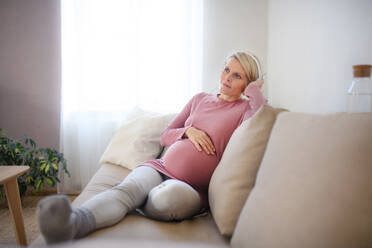Pregnant woman sitting in a bed, listening music and enjoying time for herself. - HPIF11676