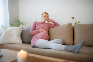 Pregnant woman sitting in a bed, listening music and enjoying time for herself. - HPIF11677