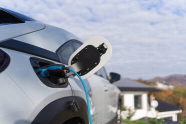 Charging electric car with own charger in house, sustainable transportation concept. - HPIF11688