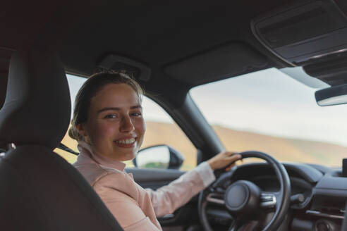 Rückansicht einer jungen Frau, die ein Elektroauto fährt. - HPIF11726