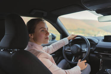 Excited young woman driving electric car. - HPIF11727