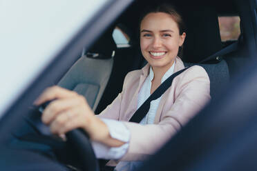 Excited young woman sitting in her car, prepared for a drive. - HPIF11729